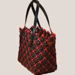 Handwoven plastic wire tote bag in black and red floral pattern with shoulder straps